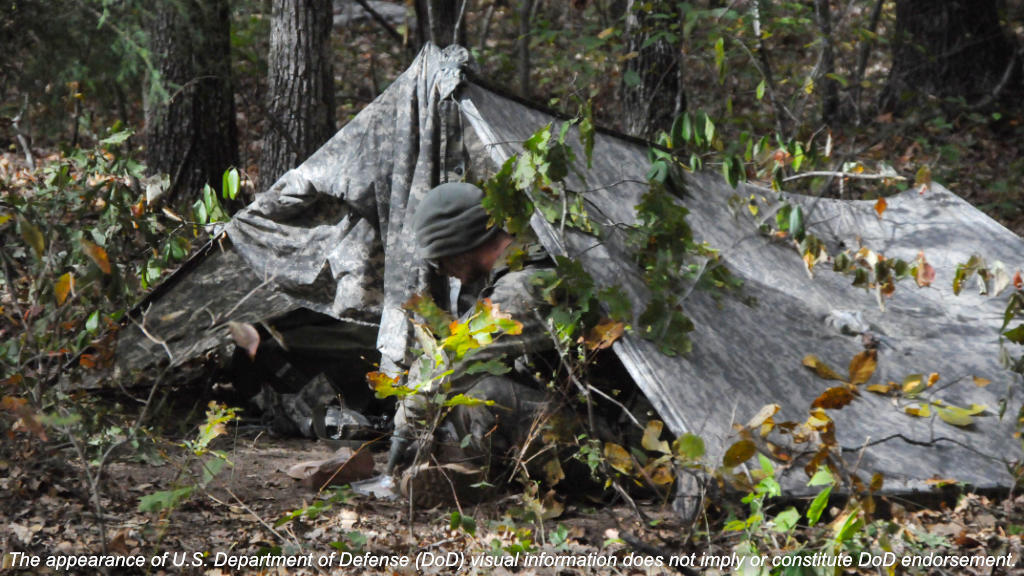 Soldier in army poncho shelter
