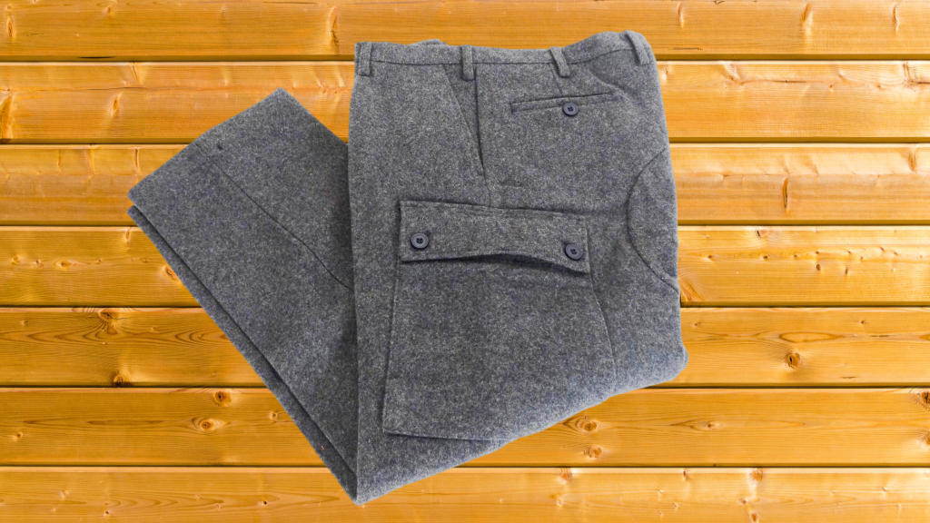 wool military pants with cargo pockets, functional expression, laid flat on a wooden background, Cinematic, close-up shot of utility pockets, highly detailed, contrasting textures, natural lighting, shot with a macro lens.